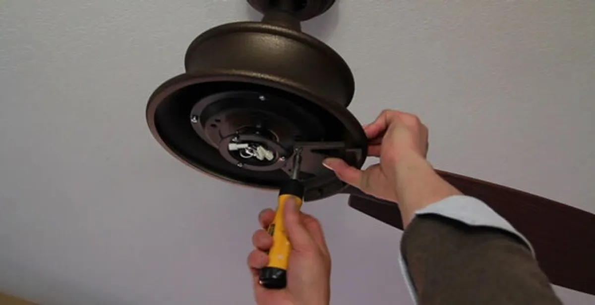 Electrician installing ceiling fan mounting bracket and fixture in Bellevue, NE
